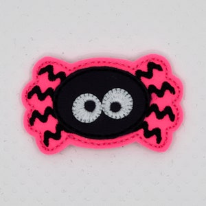 May include: Pink felt spider with black zig-zag legs and black eyes with white pupils.