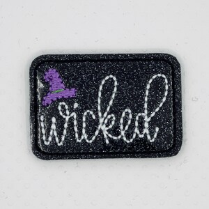 May include: Black glitter iron-on patch with white embroidery that says "wicked" and a purple witch hat.