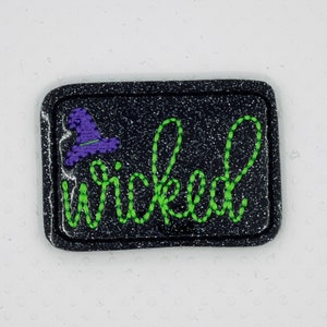 May include: Black glitter iron-on patch with green embroidered text that says "wicked" and a purple witch hat with a black brim.