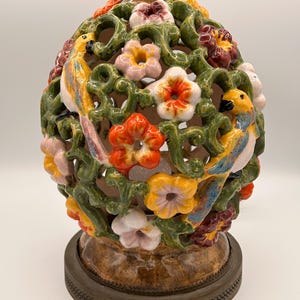 May include: A ceramic decorative lamp with a brown base and top. The lamp features a floral and bird design with colourful flowers and two birds. The lamp is painted with yellow, orange, pink, and green colours.