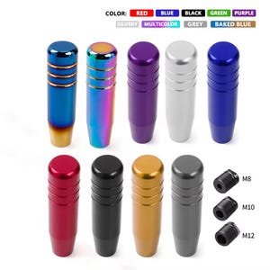 May include: A selection of car gear shift knobs in colours such as red, blue, and black. The knobs have a cylindrical shape with a metallic finish. The image also shows thread sizes: M8, M10, and M12.