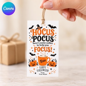 Può includere: Un'etichetta regalo rettangolare bianca con spago di juta, caratterizzata da grafiche di Halloween arancioni e nere. Il testo recita Hocus Pocus here's some coffee to help you FOCUS! Boo, Happy Halloween, from, Your Name, con zucche, pipistrelli e una tazza.