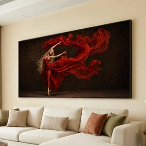 May include: A rectangular wall art print featuring a dancer with long blonde hair wearing a flowing red dress. The dancer is captured in a dynamic pose against a dark, textured background, with the fabric of the dress billowing out to the right.