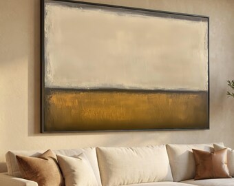 May include: A large rectangular wall art piece in a dark frame featuring an abstract landscape with a wide band of cream and beige at the top and a textured, deep golden-brown horizontal section across the bottom half of the canvas.