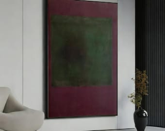 May include: Large abstract painting with a dark green square on a burgundy background, framed in black. The artwork hangs on a white wall, with a modern chair and a black vase with plants in the corner.