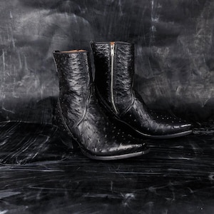 May include: A pair of black leather ankle boots with a textured, dotted pattern. The boots have pointed toes, a zipper closure, and a stacked heel. The boots are approximately 20 cm tall.