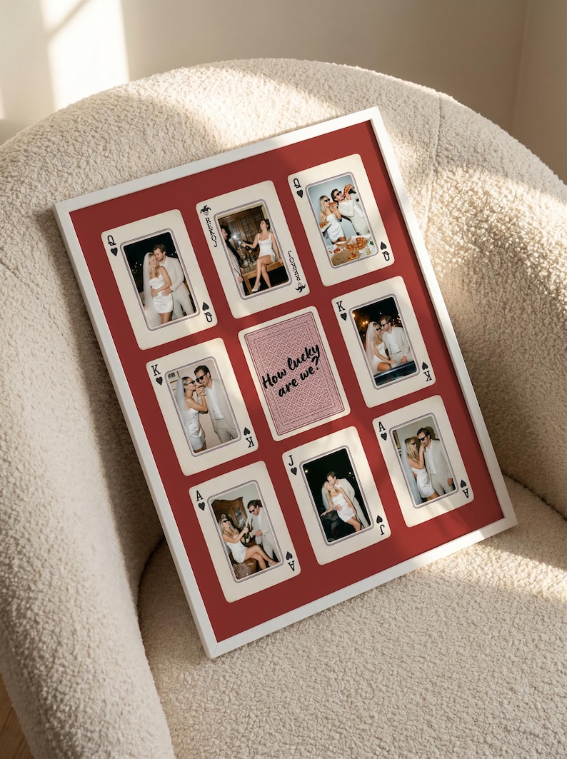 May include: A rectangular white-framed wall art piece featuring a red background with eight playing card designs and a central card back graphic. Each card displays a photograph of a couple. The center card features the text How lucky are we?