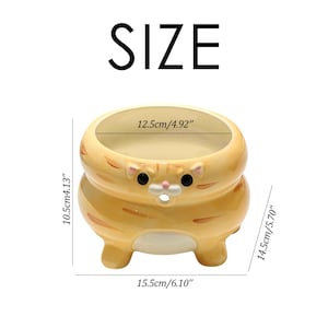 以下が含まれることがあります： オレンジとクリーム色のセラミック製の猫型プランター。黒い目と小さな鼻が特徴です。プランターの幅は15.5cm、高さは10.5cm、奥行きは14.5cmです。開口部の幅は12.5cmです。「SIZE」の文字が上部にあります。