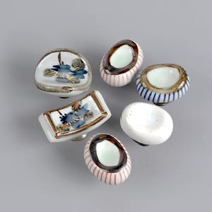 以下が含まれることがあります： 様々な形のセラミック製キャビネットノブ6個セット。青い花の模様が施されたノブもあれば、ストライプや無地の白の模様のノブもあります。家具や室内装飾用にデザインされたノブです。