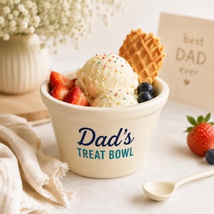 Pu&ograve; includere: Una ciotola in ceramica color crema con la scritta blu scuro Dad's TREAT BOWL stampata sul davanti. La ciotola &egrave; riempita con due palline di gelato alla vaniglia guarnite con zuccherini colorati, un biscotto a cialda, fragole e mirtilli.