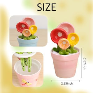 May include: A set of ceramic measuring spoons shaped like colorful flowers in a small pot. The pot is pink and measures 2.95 inches wide and 2.67 inches tall. The image also shows a blue pot with the same flower spoons and a pink pot with a dragonfly.