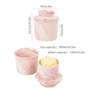 Puede incluir: Una mantequera de cer&aacute;mica rosa y blanca veteada con tapa, que mide 10 cm de di&aacute;metro y 10,5 cm de alto. La mantequera se muestra con y sin mantequilla, y la capacidad de la taza es de 300 ml, y la capacidad de la mantequilla es de 150 ml.