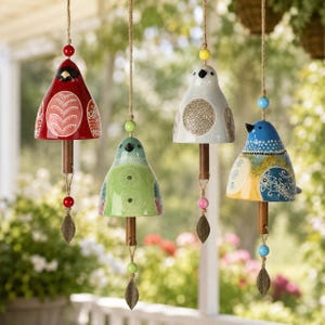 Puede incluir: Cuatro carillones de viento de cerámica con forma de pájaro colgados de un cordel. Cada pájaro presenta patrones y colores únicos: rojo, verde claro, gris claro y azul. Cada carillón incluye un badajo de madera, cuentas y una hoja de metal.