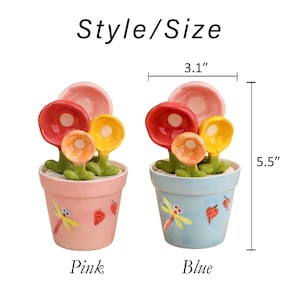 May include: Two ceramic flower pot decorations, one pink and one blue, each with three colorful flower-shaped elements. The pink pot has a dragonfly and strawberry design, and the blue pot has a dragonfly and strawberry design. The pots are 5.5 inches tall and 3.1 inches wide.