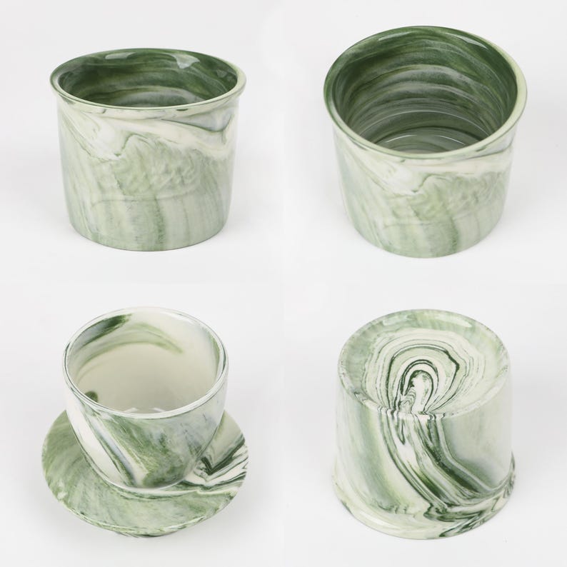 Puede incluir: Un juego de cuatro tazas y platillos de cer&aacute;mica con un dise&ntilde;o veteado en verde y blanco. Las tazas son cil&iacute;ndricas con un borde ligeramente ensanchado. Los platillos son redondos y combinan con el dise&ntilde;o de la taza.