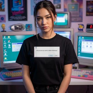 Pode incluir: Uma t-shirt preta de manga curta com um gráfico retangular branco no peito que imita uma caixa de diálogo de computador. O texto dentro da caixa diz: "Are you sure you want to delete all feelings?" com botões "Yes" e "No" abaixo.