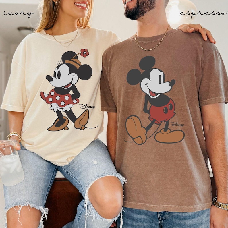 Puede incluir: Dos camisetas, una marfil y otra espresso, con Mickey y Minnie Mouse. La camiseta marfil tiene a Minnie Mouse con un vestido de lunares rojos. La camiseta espresso tiene a Mickey Mouse con pantalones cortos rojos. Ambas camisetas tienen el logo de Disney.