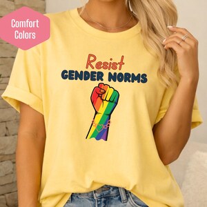 May include: Yellow t-shirt with the words "Resist GENDER NORMS" and a rainbow fist graphic. The shirt also has a pink label that says "Comfort Colors".