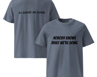 May include: Two blue t-shirts. One has the text "ALL HUMANS ARE HUMAN" on the back. The other has the text "NOBODY KNOWS WHAT WE'RE DOING" on the front. Both are short-sleeved, casual wear.