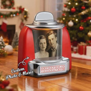 Op de afbeelding: Rode en zilveren fotolijst in retrostijl met een zwart-witfoto van een stel. De lijst heeft een chromen boven- en onderkant, met een selectie letters en cijfers. Tekst luidt "Custom Photo & Music".