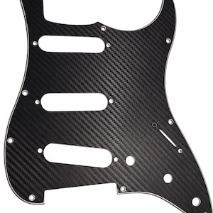 Puede incluir: Golpeador de guitarra de fibra de carbono negro con tres recortes para pastillas, una cavidad de control y orificios de montaje. El golpeador tiene una superficie texturizada y un borde blanco.