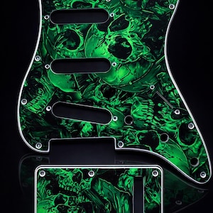 Puede incluir: Un juego de golpeador y placa de control para guitarra con un vibrante patr&oacute;n de calaveras verdes. El golpeador tiene tres recortes para pastillas y m&uacute;ltiples orificios para tornillos. La placa de control tiene un solo recorte.
