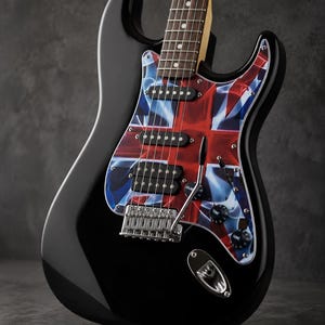 May include: A black electric guitar featuring a pickguard with a red, white, and blue Union Jack flag pattern. The instrument includes three black pickups, a chrome bridge, a tremolo arm, and two black control knobs on the glossy black body.