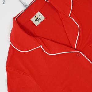 Pu&ograve; includere: Una tazza di ceramica bianca con manico nero e la scritta "But First, Coffee" in grassetto nero. La tazza &egrave; posta su uno sfondo sfocato, suggerendo un'atmosfera accogliente.