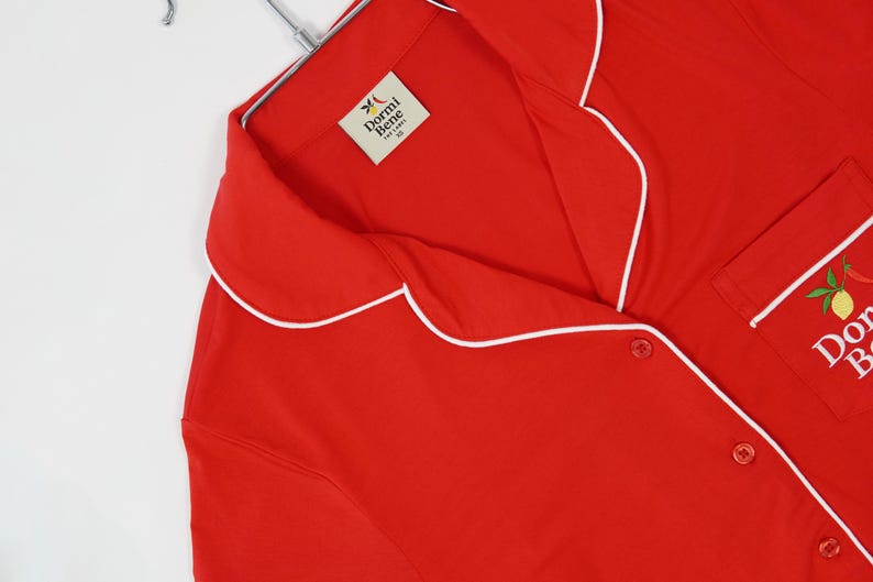 Pu&ograve; includere: Una tazza di ceramica bianca con manico nero e la scritta "But First, Coffee" in grassetto nero. La tazza &egrave; posta su uno sfondo sfocato, suggerendo un'atmosfera accogliente.