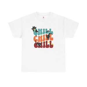May include: White t-shirt featuring the word "CHILL" in teal, orange, and red, with black cat illustrations. The cats are in various poses, and the design has a playful, cartoonish style. The shirt has a crew neck and short sleeves.