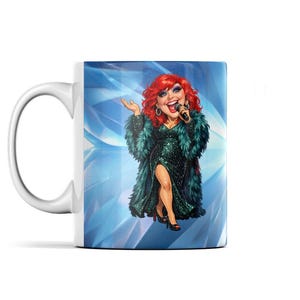 May include: White ceramic mug featuring a cartoon illustration of a red-haired performer in a green sequined dress and feathered boa, holding a microphone. The background is a blue, geometric design.