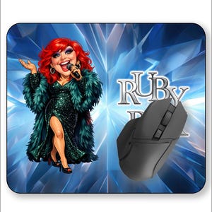 May include: A black computer mouse rests on a mousepad featuring a cartoon of a woman with red hair and a green sequined dress, holding a microphone. The mousepad has the text "Ruby" and a blue background.