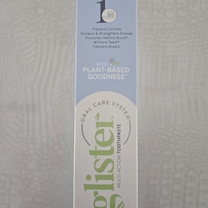 Op de afbeelding: Een lichtblauwe en witte doos met Glister multi-action tandpasta. De tekst luidt: "Voorkomt gaatjes, Beschermt & versterkt glazuur, Bevordert gezond tandvlees, Maakt tanden witter, Verfrist de adem." Netto gewicht: 200 g.