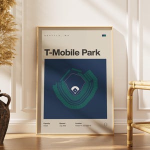 May include: Framed poster of T-Mobile Park in Seattle, WA. The poster features a detailed diagram of the baseball stadium in green and white on a navy blue background. The poster includes the stadium's name, location, and opening date.