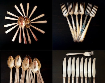 May include: A set of vintage silverware, including forks, spoons, and knives, arranged in a grid pattern. The silverware is silver-toned and has a worn, antique look.