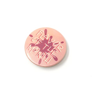 May include: A pink button with a red splatter design and the text "Flavor of the Month" in white.