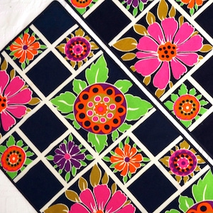 May include: Two black and white patterned fabric placemats with a geometric design featuring pink, orange, green, and purple flowers.