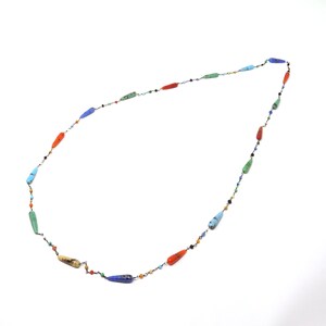 May include: A long necklace with a silver chain and colorful teardrop-shaped beads. The beads are in shades of blue, green, orange, and red.