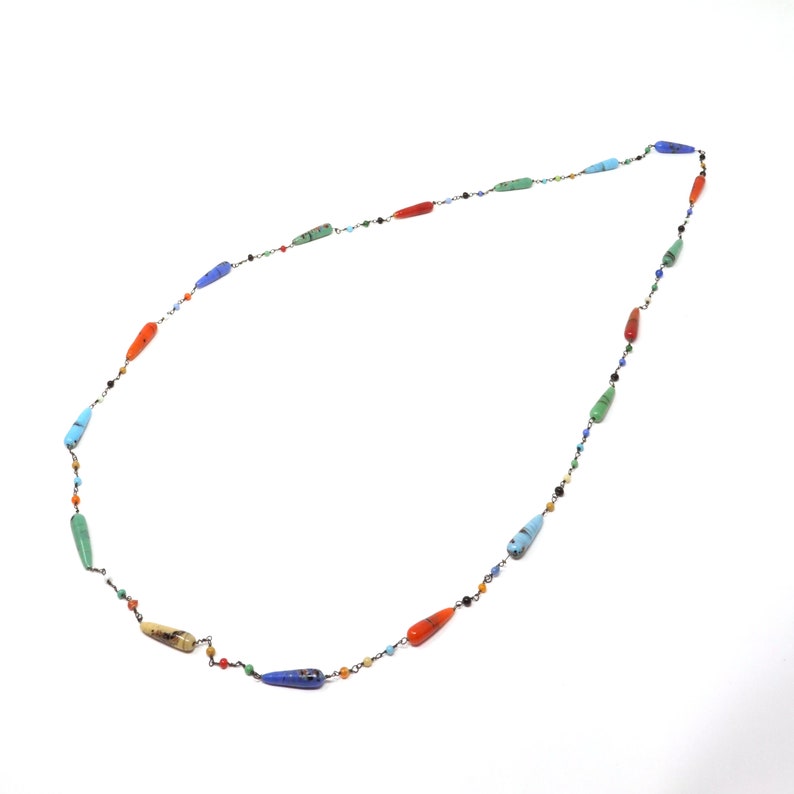 May include: A long necklace with a silver chain and colorful teardrop-shaped beads. The beads are in shades of blue, green, orange, and red.
