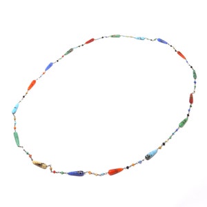 May include: A long necklace made of silver chain with various colored gemstone beads. The beads are in the shape of teardrops and are red, orange, yellow, green, blue, and purple.