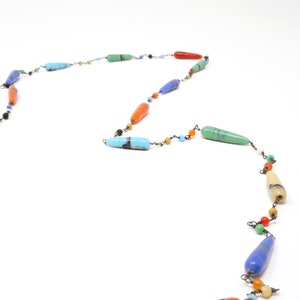 May include: A colorful necklace with long, teardrop-shaped beads in various shades of blue, green, orange, and yellow. The beads are strung on a thin wire with small, round beads in between.