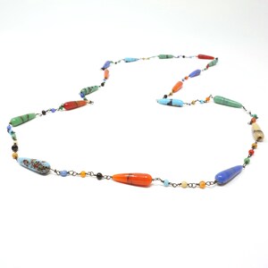 May include: A long necklace with a variety of colorful glass beads. The beads are teardrop shaped and have a variety of colors, including blue, green, orange, and yellow.