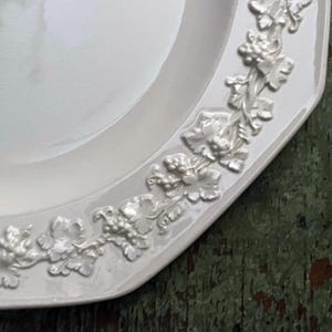 May include: White ceramic serving platter with a raised design of grape vines and leaves around the edge.