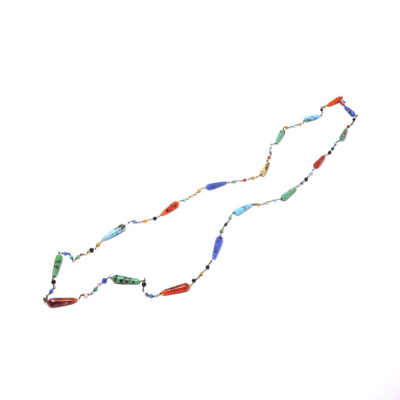May include: A long necklace with colorful, teardrop-shaped beads. The beads are made of various gemstones, including turquoise, red jasper, and carnelian.