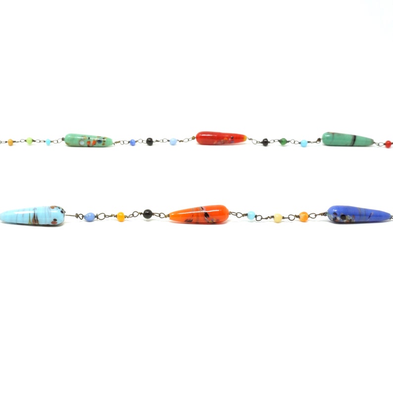 May include: A colorful glass bead necklace with a variety of colors, including blue, green, orange, and red. The beads are strung on a thin metal chain.