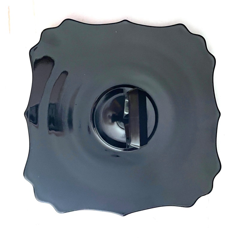 May include: A black glass serving plate with a scalloped edge and a center indentation. The plate is designed for serving desserts or snacks.