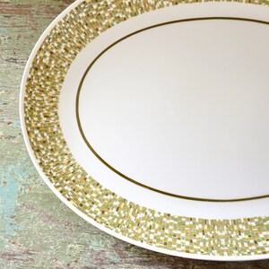 May include: A white oval serving platter with a gold and green geometric pattern around the edge.