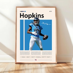May include: Framed poster featuring a football player in a blue uniform, holding a football. The poster has the name "Hopkins" in large black letters, with a signature and statistics below. The background is light blue.