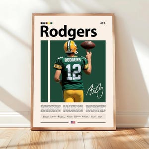 May include: A framed poster with a football player in a green and yellow uniform, with the name "Rodgers" in large black letters. The player is holding a football. The poster includes the number 12 and a signature.