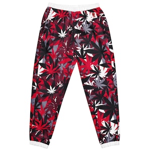 May include: Jogger-style pants with a repeating pattern of red, black, white, and gray cannabis leaves. The pants have a white elastic waistband and cuffs. The overall design is a bold and eye-catching print.